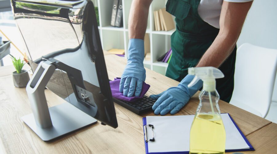 office cleaner wiping down computer keyboard